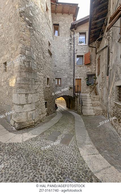cityscape with bending street and arched passage in little historical town , shot in bright fall light at Arco, Trento, Italy