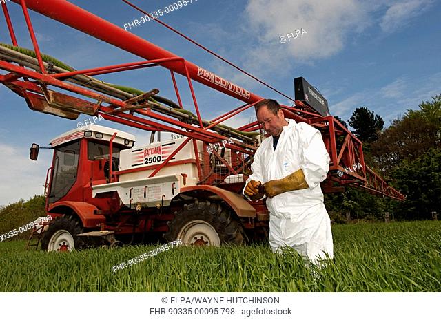 Sprayer operator in protective clothing, checking nozzles on Bateman 2500 self-propelled sprayer, County Durham, England