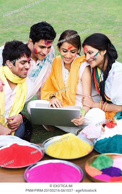 Friends celebrating Holi and using a laptop