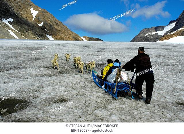 Dog-sledge with Husky dogs guests and an Inuit Greenlander on glacier Apusiak Eastgreenland