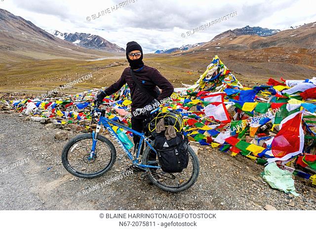A bicyclist stops at the summit of 16, 000 foot Bara-lacha Pass, Leh-Manali Highway, Himachal Pradesh, India