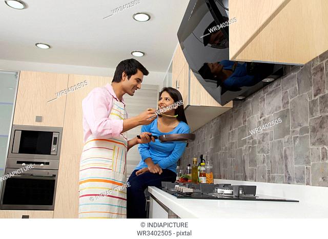 Indian couple cooking food in kitchen