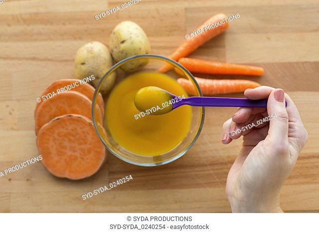 hand with vegetable puree or baby food in spoon