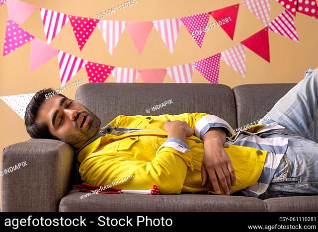 Young man sleeping on sofa after being drunk at party