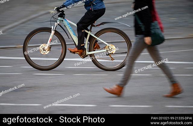 21 October 2020, Baden-Wuerttemberg, Stuttgart: An e-bike rider overtakes a pedestrian in morning traffic. Today the German Pedestrian Congress takes place
