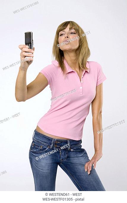 Young woman photographing self using camera phone, pouting, close-up