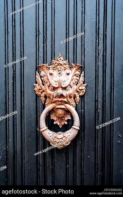 Antique door handle in the form of a demonic image with a ring in the mouth in gilding. High quality photo