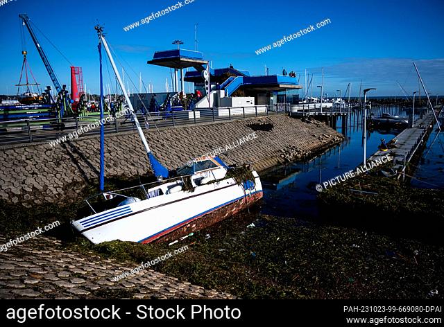 23 October 2023, Schleswig-Holstein, Kiel-Schilksee: A damaged ship lies at the edge of the harbor after a storm surge in the Schilksee Olympic harbor