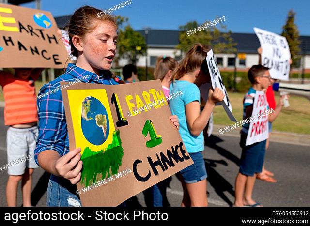 Side view of a group of Caucasian elementary school pupils on a protest march, carrying signs with environmental and conservation slogans on them