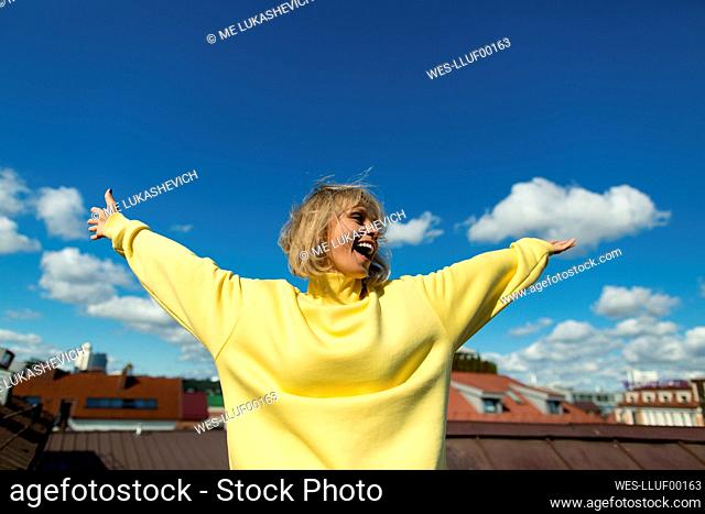 Carefree woman with arms outstretched having fun on rooftop