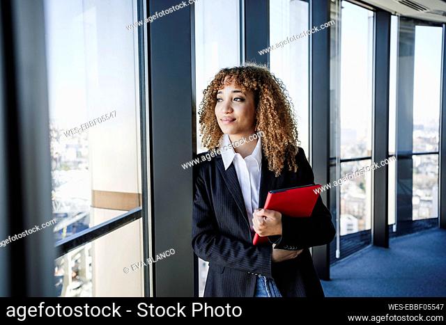 Businesswoman with tablet PC looking out of window in office