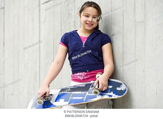 Mixed Race girl holding skateboard
