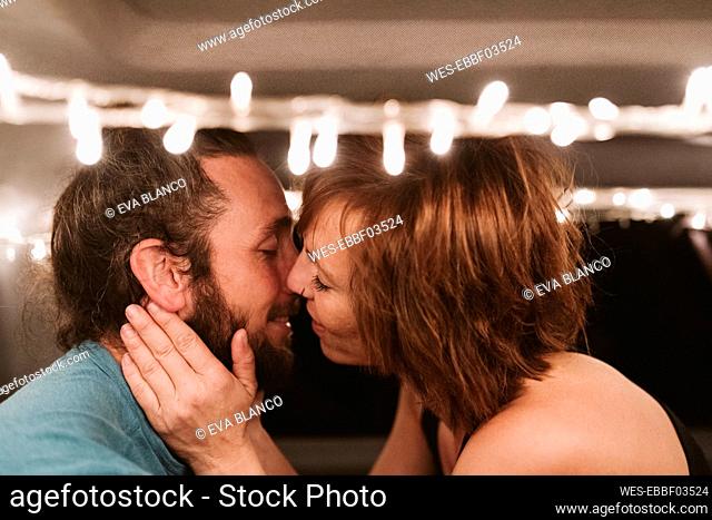 Romantic couple kissing in illuminated van at night