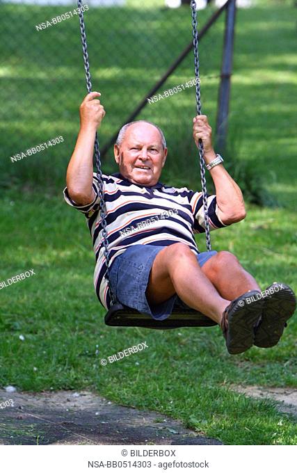 Laughing senior on swing