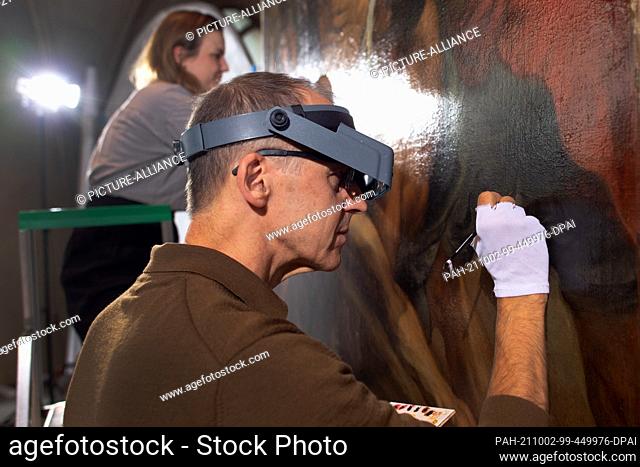 10 September 2021, North Rhine-Westphalia, Cologne: Andreas Hoppmann (r) and Fanny Weber, restorers, work on the painting ""The Crucifixion of Peter"" by Peter...