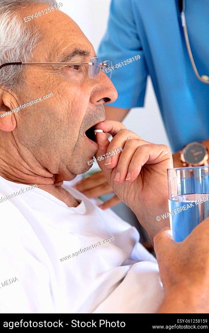 Caucasian senior man eating medical pills lying on the bed at home