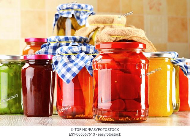 Composition with jars of marinated food. Pickled vegetables and jams