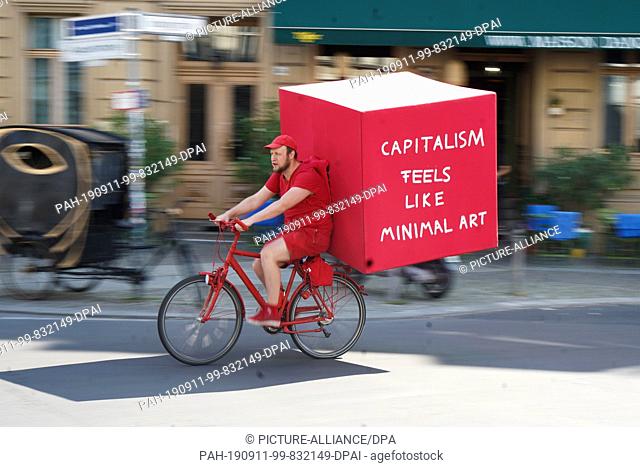 11 September 2019, Berlin: As part of Berlin Art Week, artist Daniel Chluba rides through the city on a red bicycle with a large red box on his back