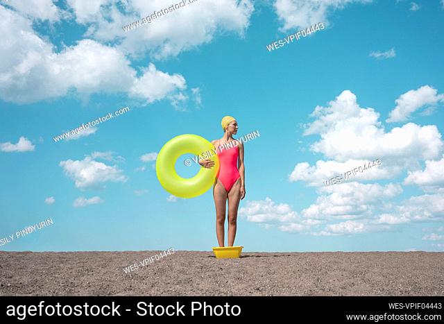 Woman holding yellow swimming tube while standing at beach