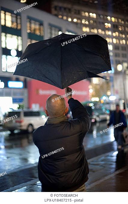 Man holding up an umbrella in Manhattan, New York City, U.S.A