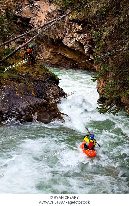 A male kayaker dropping a waterfall on Johnston Canyon, Banff National Park, AB