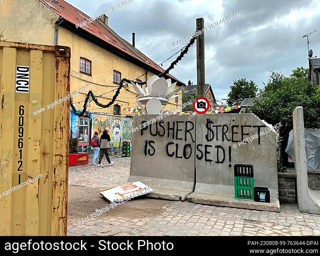 08 August 2023, Denmark, Kopenhagen: ""Pusher Street is closed!"" (Pusher Street is closed) is written on a blockade in the Copenhagen free city of Christiania