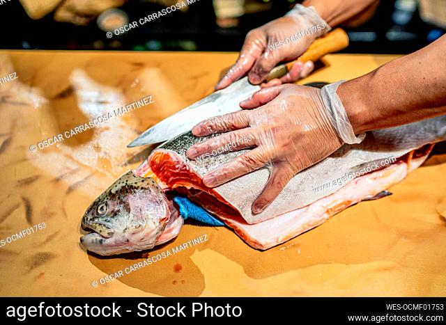 Male chef cutting fish at counter in restaurant