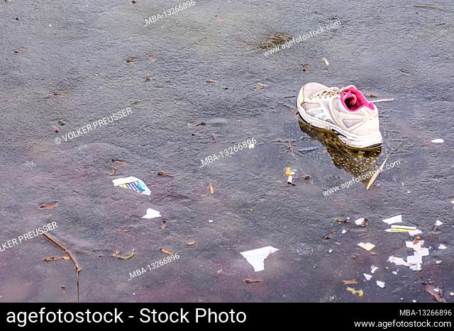 Austria, Vienna, thrown away jogging shoe on frozen lake, trash in 22. Donaustadt