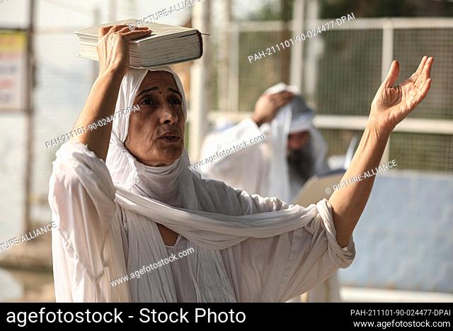 01 November 2021, Iraq, Baghdad: A Mandaean woman performs a prayer during a baptism ritual as members of the Mandaean community gather at the banks of the...