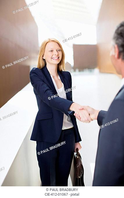 Smiling businesswoman shaking hands with businessman