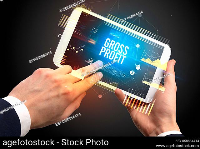 Close-up of hands holding tablet with GROSS PROFIT inscription, modern business concept