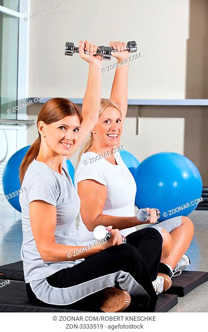 Zwei ältere Frauen trainieren mit Hanteln im Fitnesscenter
