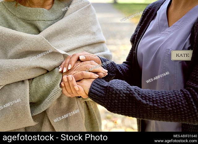 Caretaker holding hands consoling senior woman