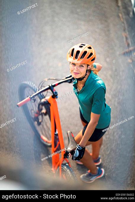 Pretty, young woman with her mountain bike going for a ride past the city limits, getting the daily cardio dose