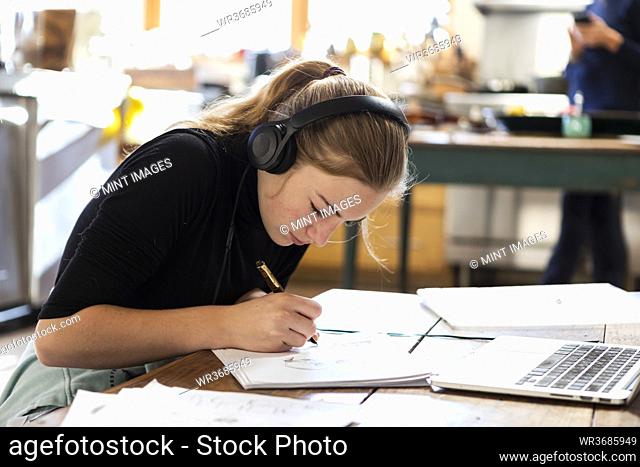 teenage girl wearing headphones, drawing on paper