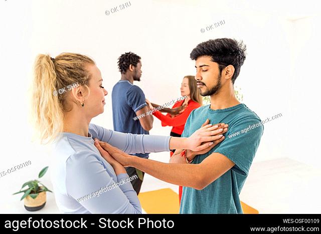 Couples with eyes closed touching chest of each other at yoga studio