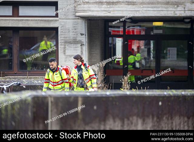 30 November 2023, North Rhine-Westphalia, Cologne: Two rescue workers from the German Red Cross come out of a school in Cologne Müngersdorf