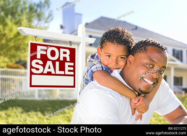 African american father and mixed-race son in front of home for sale real estate sign and new house