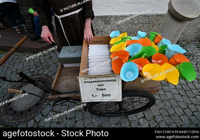 14 August 2021, Bavaria, Altötting: A monk sells candles before the beginning of the candlelight procession on the eve of the Assumption of Mary in front of the...