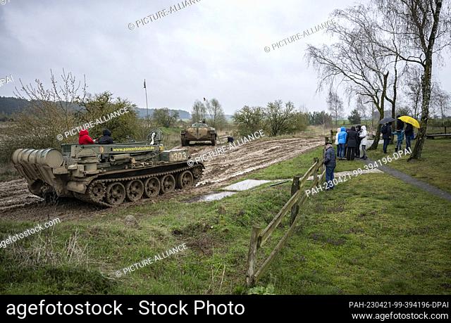 PRODUCTION - 15 April 2023, Brandenburg, Steinhöfel: People wait in front of the barrier to the training area, two people sit in a T-55TK armored recovery...