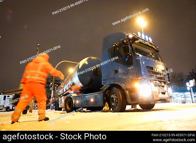 15 February 2021, Hamburg: A tanker truck is close to a traffic light and can't get any further after it slips away when starting on a glassy road at the Am...