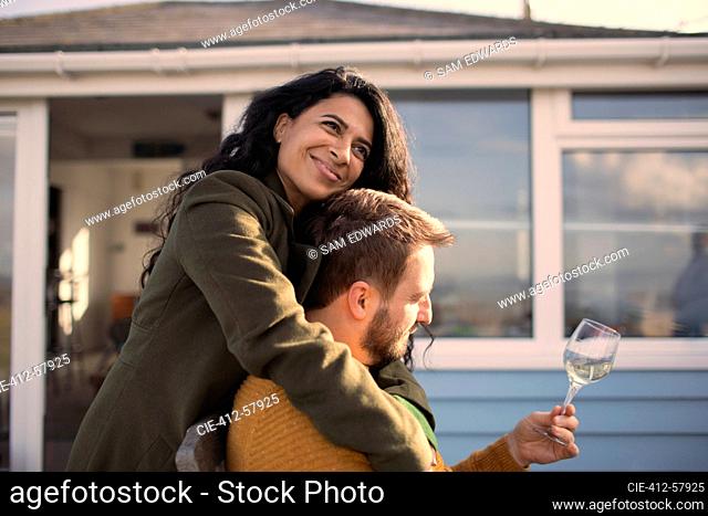 Happy couple hugging and drinking wine on patio