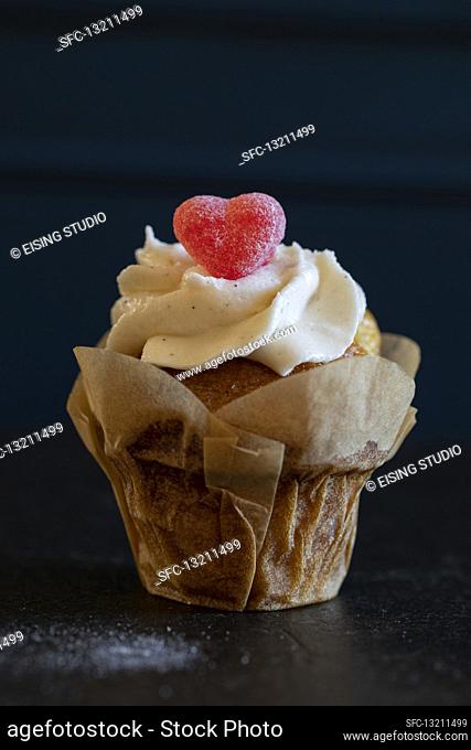 A cupcake with a gummy heart in a paper case