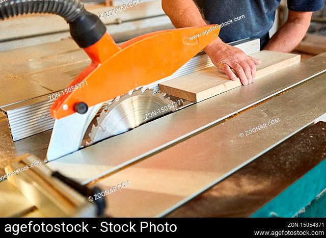 Handwerker schiebt Holz Brett auf die Kreissäge in der Tischlerei oder Schreinerei