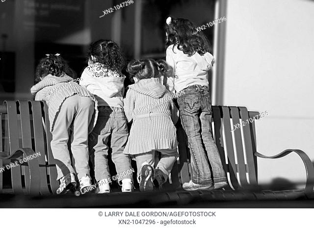 Little girls standing on a public bench