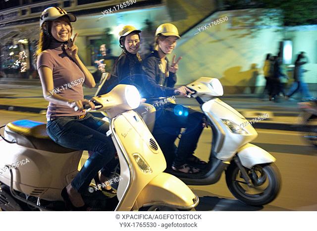 People on the streets of Vietnam at night on scooters