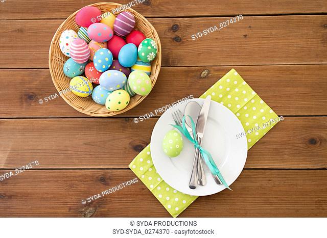 easter eggs in basket, plates, cutlery and flowers