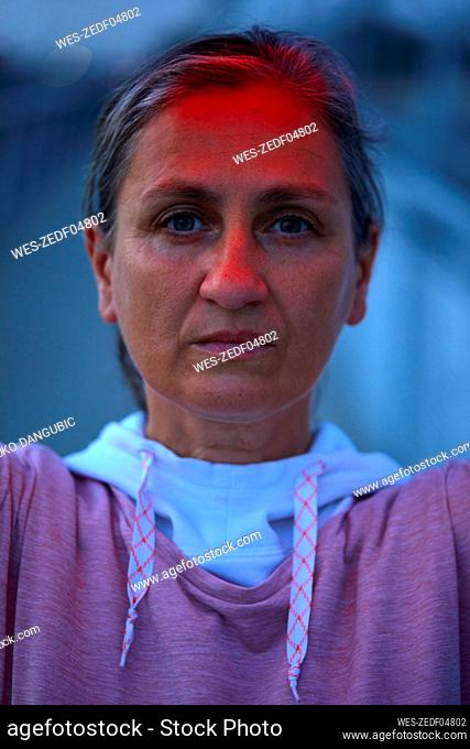 Serious woman with reflection of red light on face