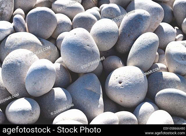 Close up of rounded bright white and grey stones at a sunny beach