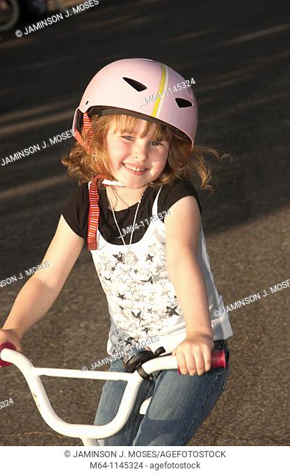 5 year old girl riding her bike with a helmet on smiling